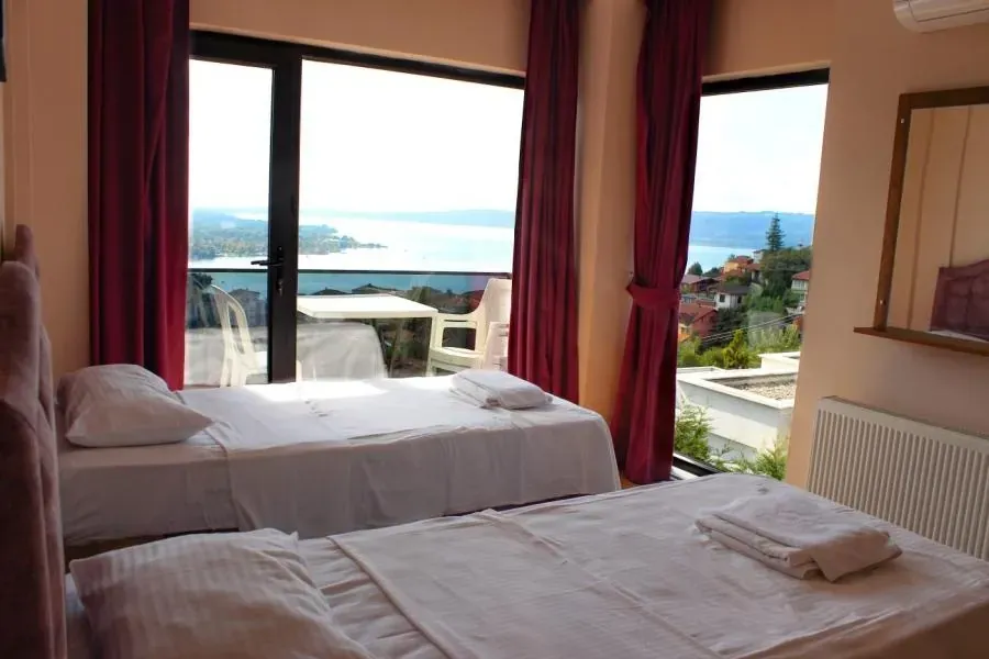 Bordo perdeli yatak odası, pencereden göl
