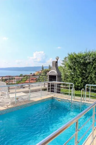Özel havuz, taş mangal bacası, korkuluk ve arkada Sapanca Gölü