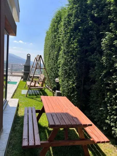 Çimde ahşap piknik masası ve banklar, yanında salıncak ve yüksek çit